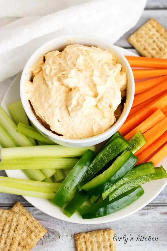 Top down view of dip in bowl with celery, peppers, and carrot sticks.