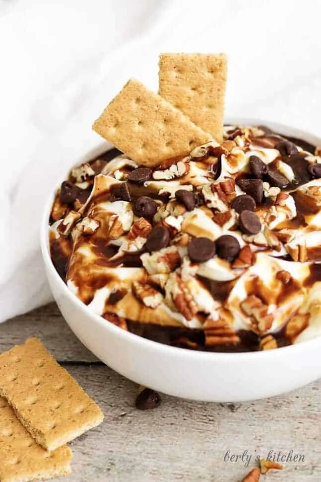 Turtle cheesecake dip with two graham crackers.