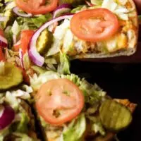 The works cheeseburger pizza is a simple to prepare recipe loaded with all the fixings, including lettuce, tomatoes, pickles, and onions.