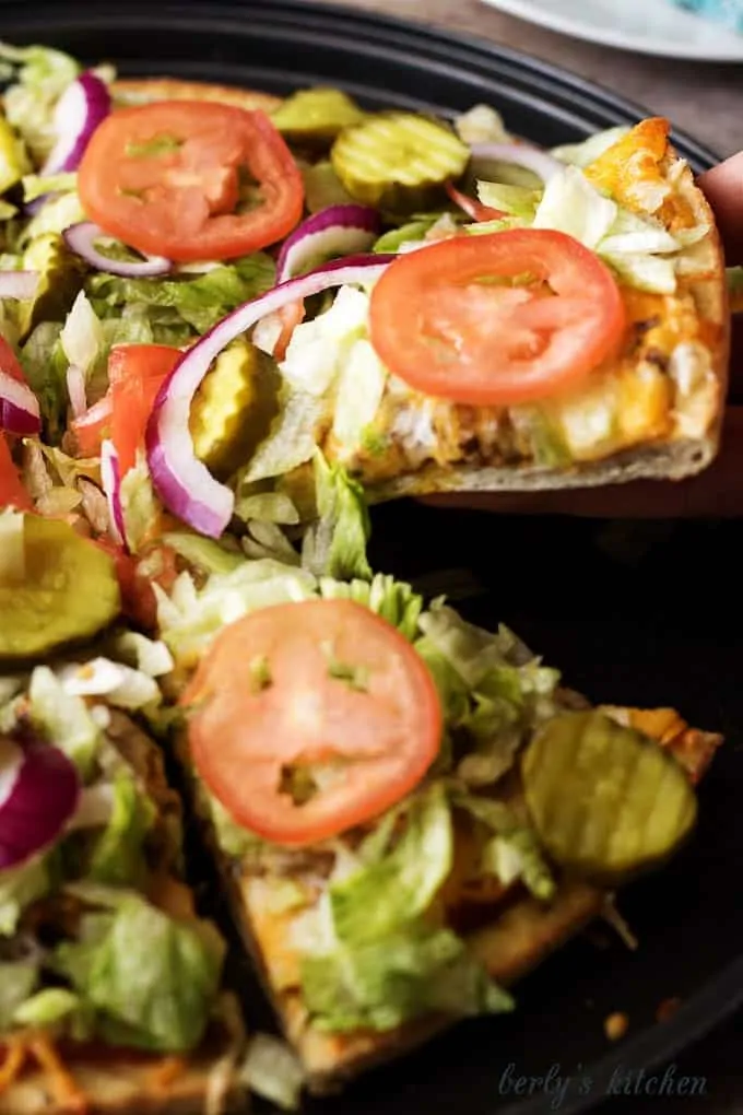 The works cheeseburger pizza is a simple to prepare recipe loaded with all the fixings, including lettuce, tomatoes, pickles, and onions.