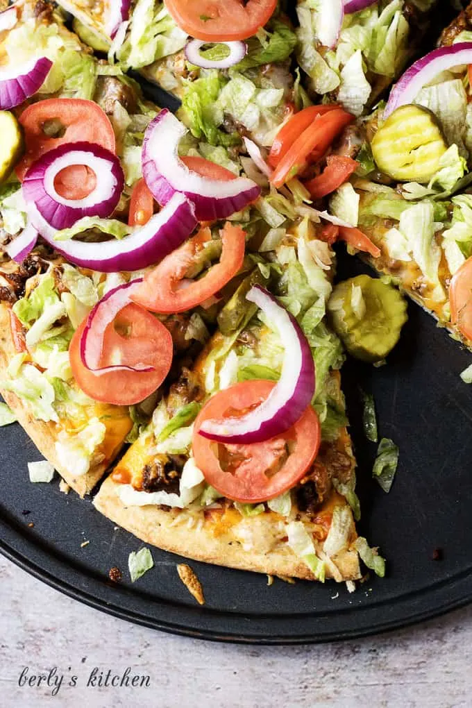 The works cheeseburger pizza is a simple to prepare recipe loaded with all the fixings, including lettuce, tomatoes, pickles, and onions.