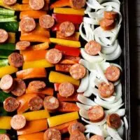 Spicy sausage and peppers in rows on a baking sheet.