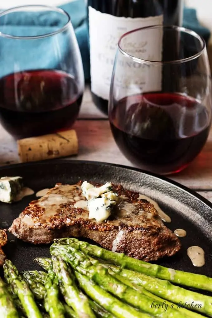 Steak and asparagus with two glasses of red wine.