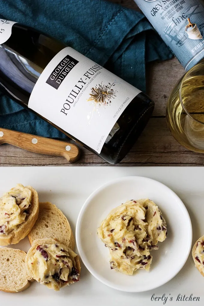 Top down view of wine bottle and cheese topping and bread slices.