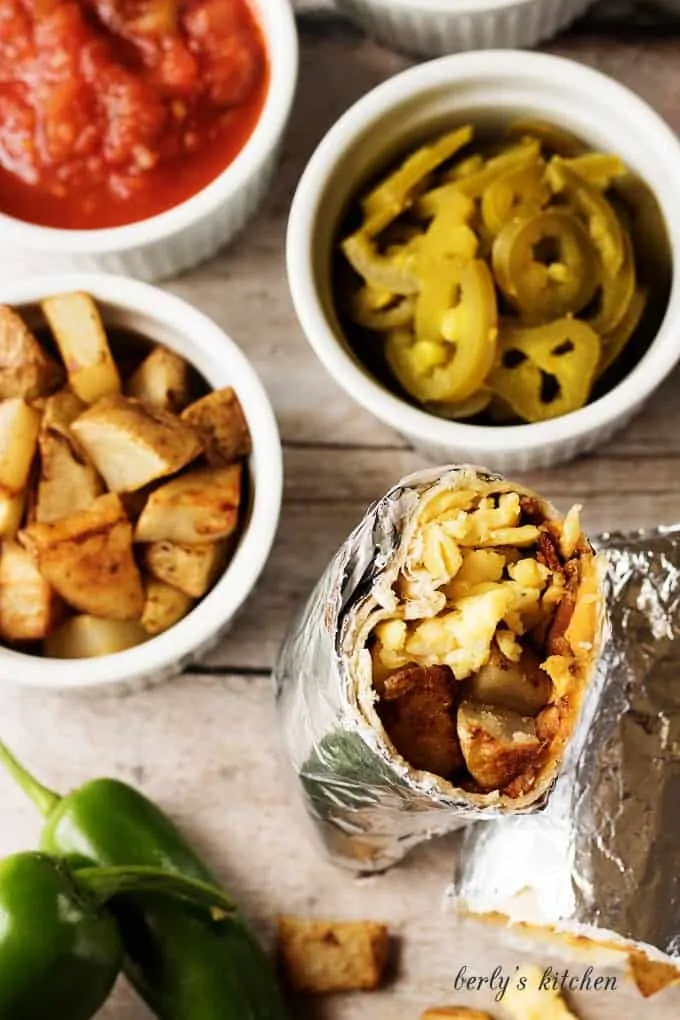 Top down view of breakfast burrito recipe, potatoes, jalapenos, and salsa.