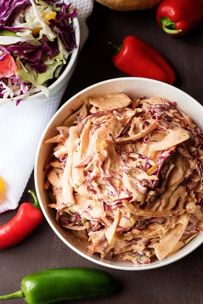 Top down view of spicy coleslaw with red and green baby peppers.