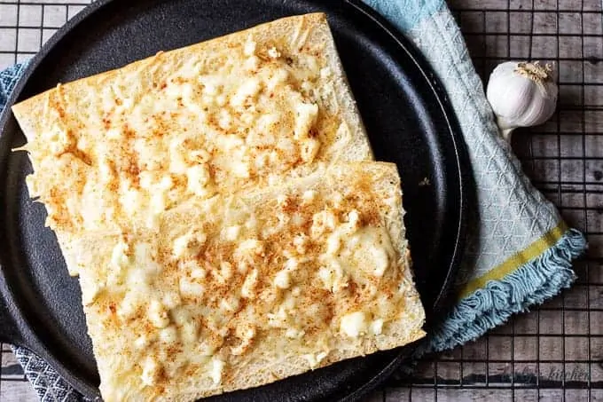 Feta mozzarella topped cheesy bread is the ultimate compliment or starter to any meal. We took cuban bread, then topped it with feta, mozzarella, and garlic.