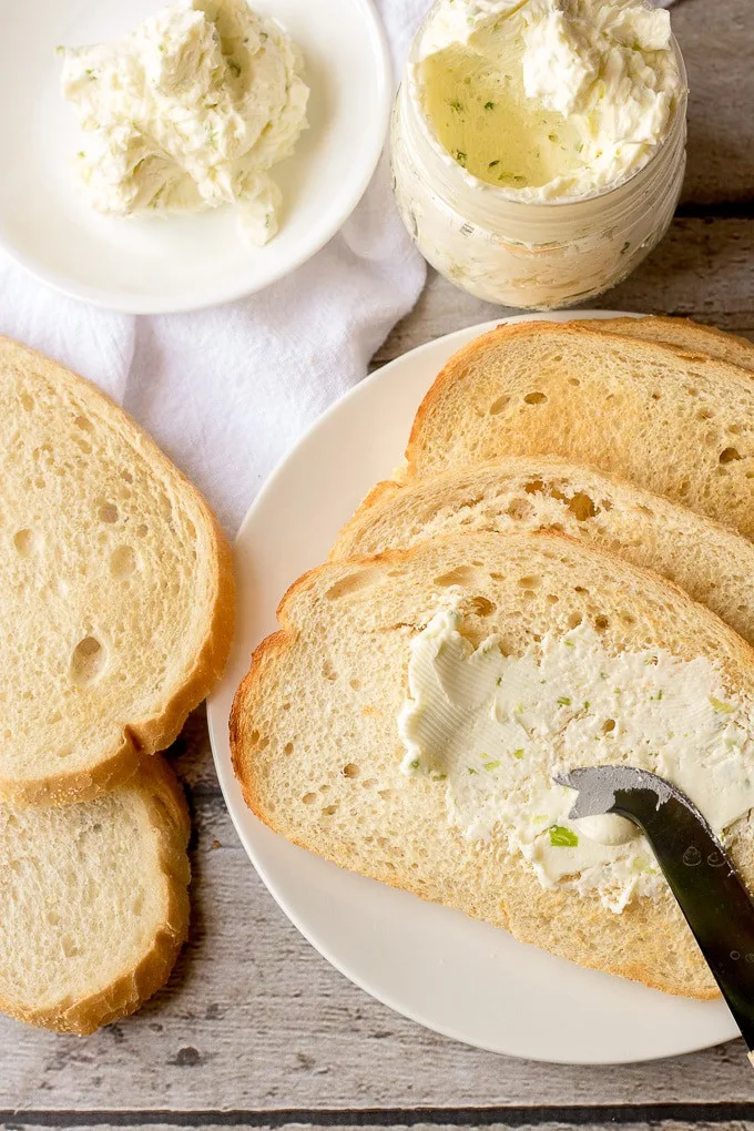 Top down view of butter on sliced bread and compound butter in jar.