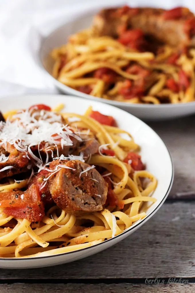 Spicy italian sausage and tomato linguine in a pasta dish topped with parmesan cheese.