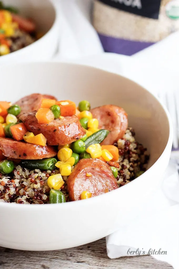 Close up of organic quinoa sausage dinner in a white bowl.