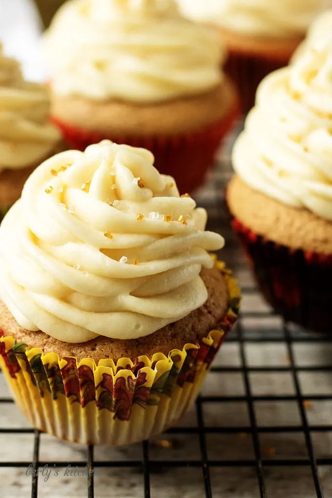 Close up of cupcakes with buttercream on a cooling rack.