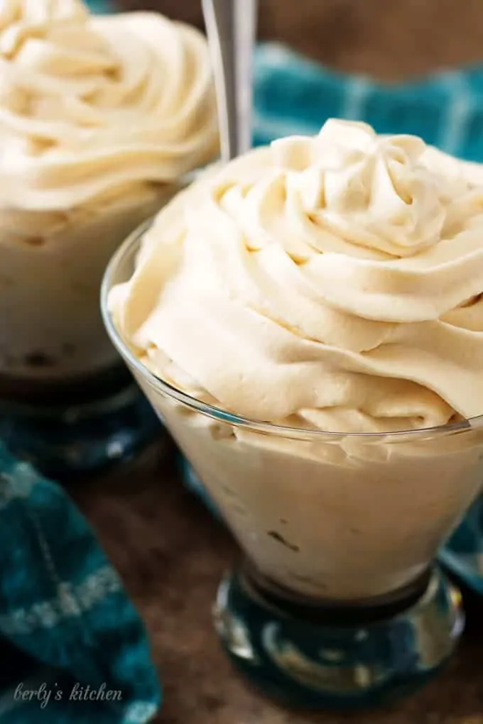 Irish cream flavored whipped cream in two cocktail glasses with blue towels.