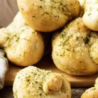 A close view of the finished parmesan-butter topped garlic knots stacked up for serving.