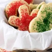 The colorful soft sugar cookies in cookie tine surrounded by decorative paper.