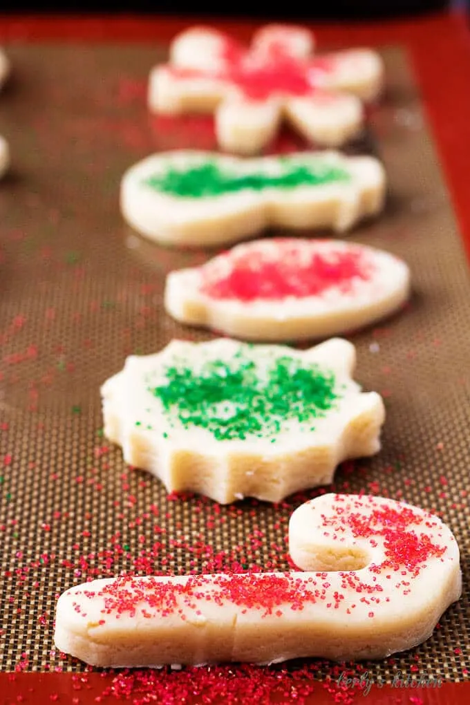 Side-view of the ornament and wreath shaped cookies on a pan, sprinkled with sugar for baking.