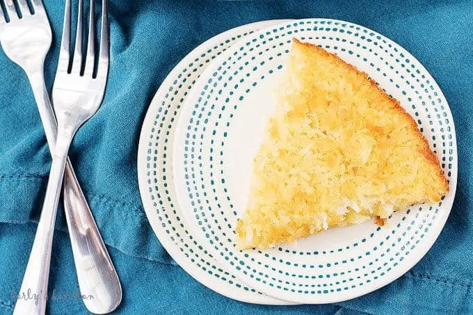 Ariel view of coconut custard pie on a blue and white plate with a blue napkin and two forks.