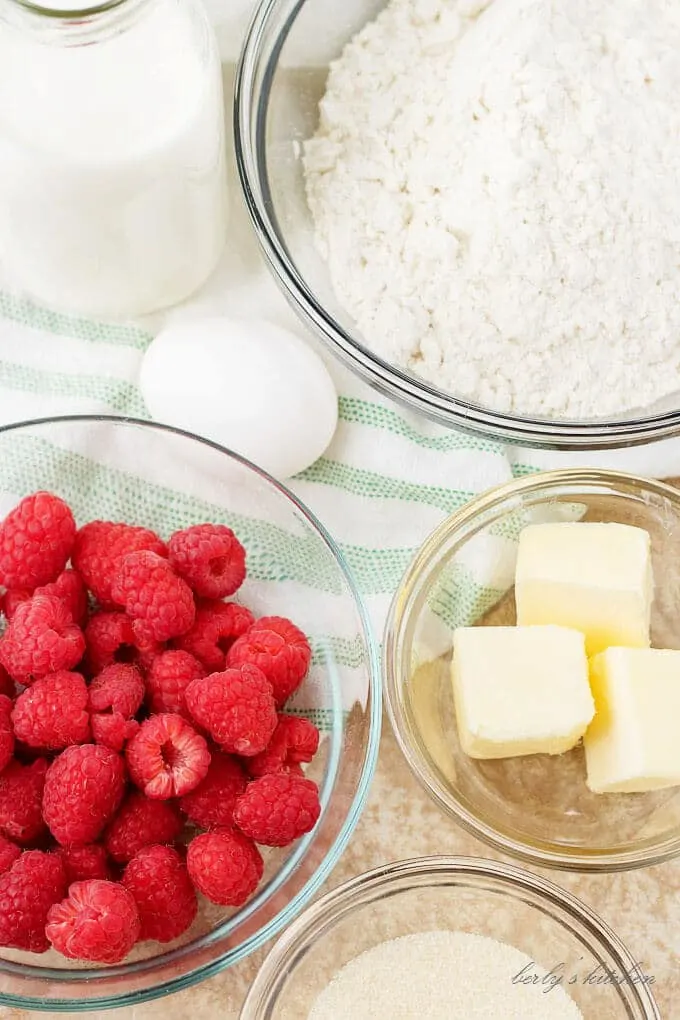 An aerial view of the ingredients, like butter, raspberries, and flour mix.