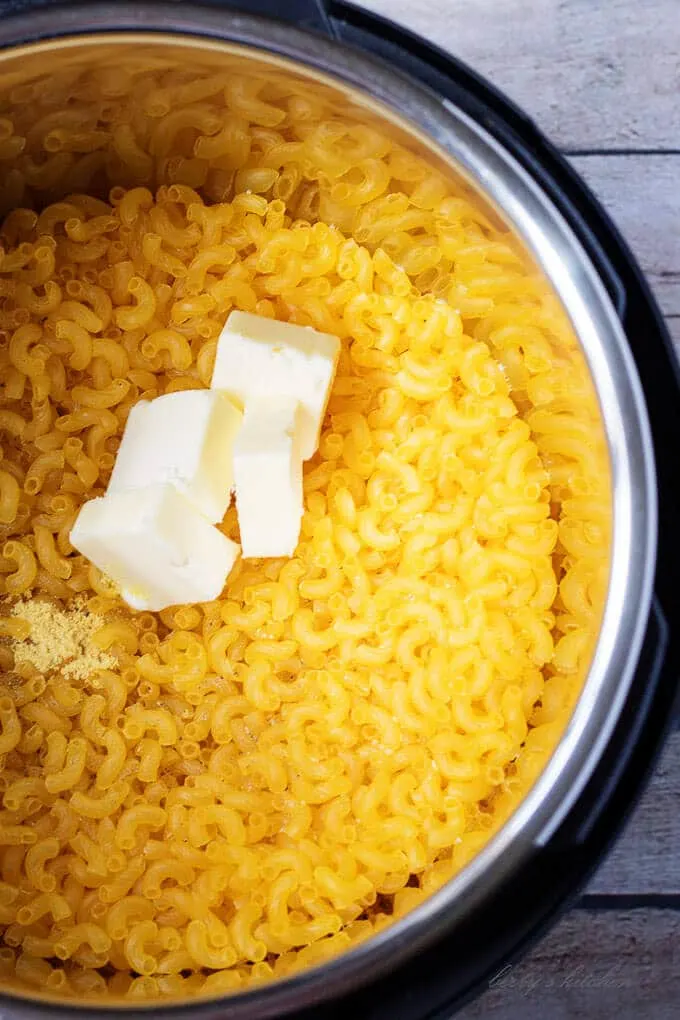 Ariel view of elbow noodles, butter, and ground mustard in an open instant pot.