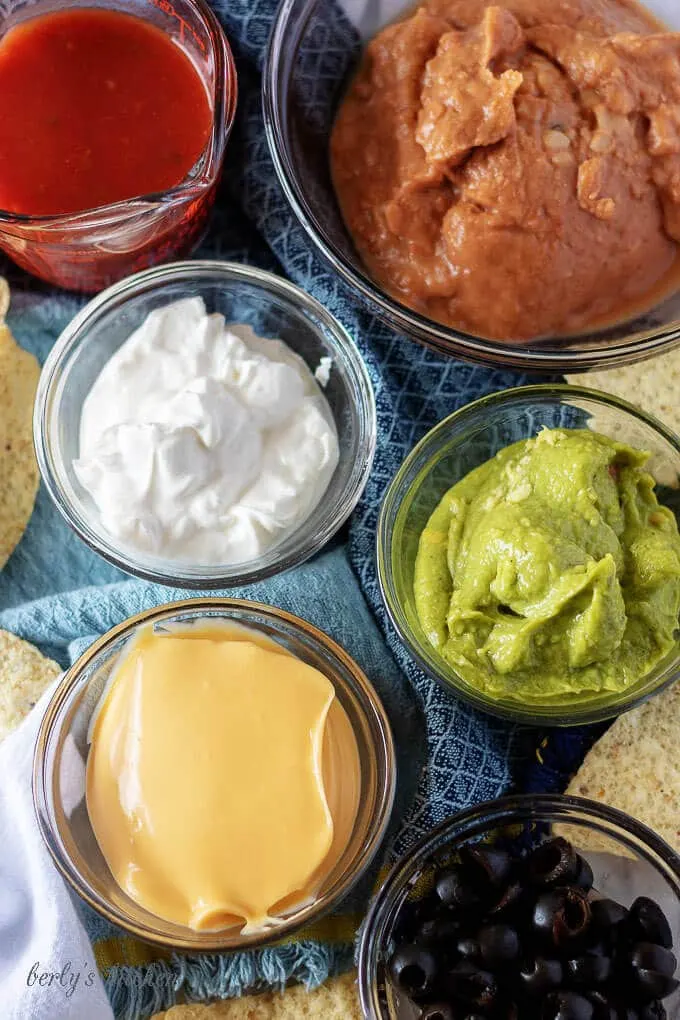 An aerial photo of the 7 layer dip ingredients like, guacamole, sour cream, and nacho cheese sauce.