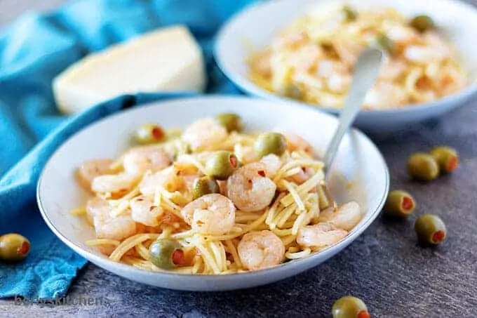 The finished shrimp and pasta in two white bowls garnished with green olives.