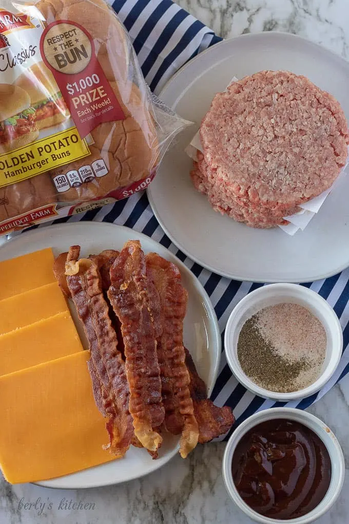 An aerial photo of the bacon cheeseburger ingredients like cheddar cheese, bacon slices, and all beef patties.