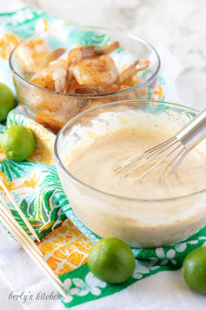 Two glass mixing bowls, one with the mixed key lime aioli, another with the raw but seasoned shrimp.