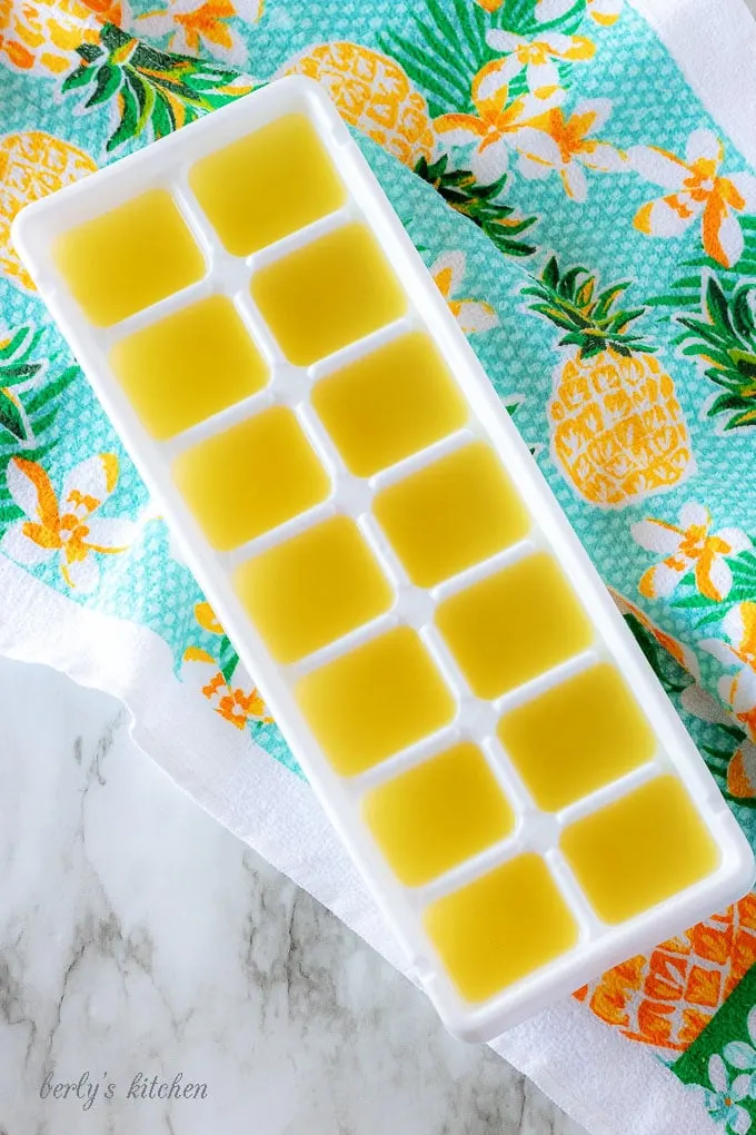 The tropical cocktail mixture poured into a white ice cube tray for freezing.