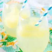 The tropical cocktail booze cubes melting in the sparkling water served in a stemless wine glass.