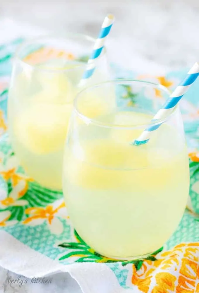 The tropical cocktail booze cubes melting in the sparkling water served in a stemless wine glass.