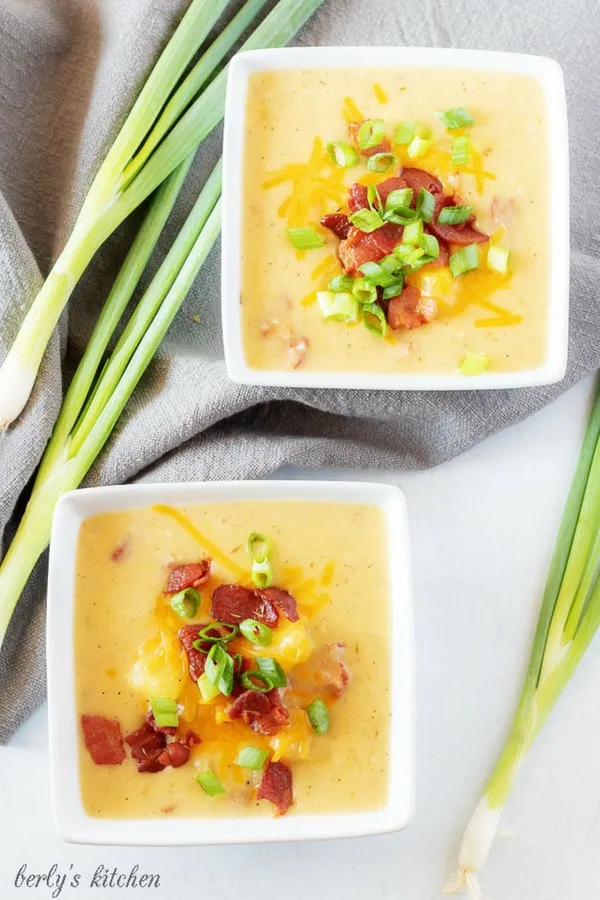 A top-down photo of the finished potato soup with bacon in bowls, topped with cheese, bacon, and onions.