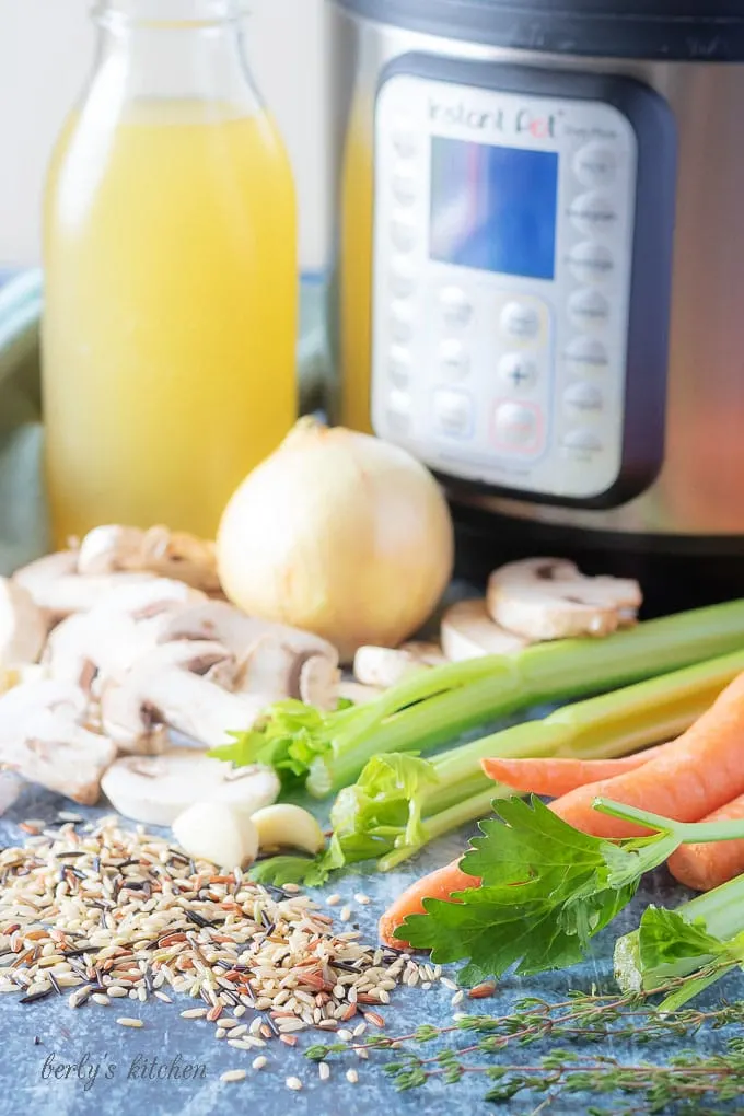 The instant pot soup ingredients like chicken broth, onions, carrots, and celery.