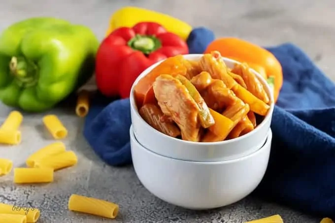 Chicken fajita pasta in stacked white bowls with bell peppers and a blue linen.