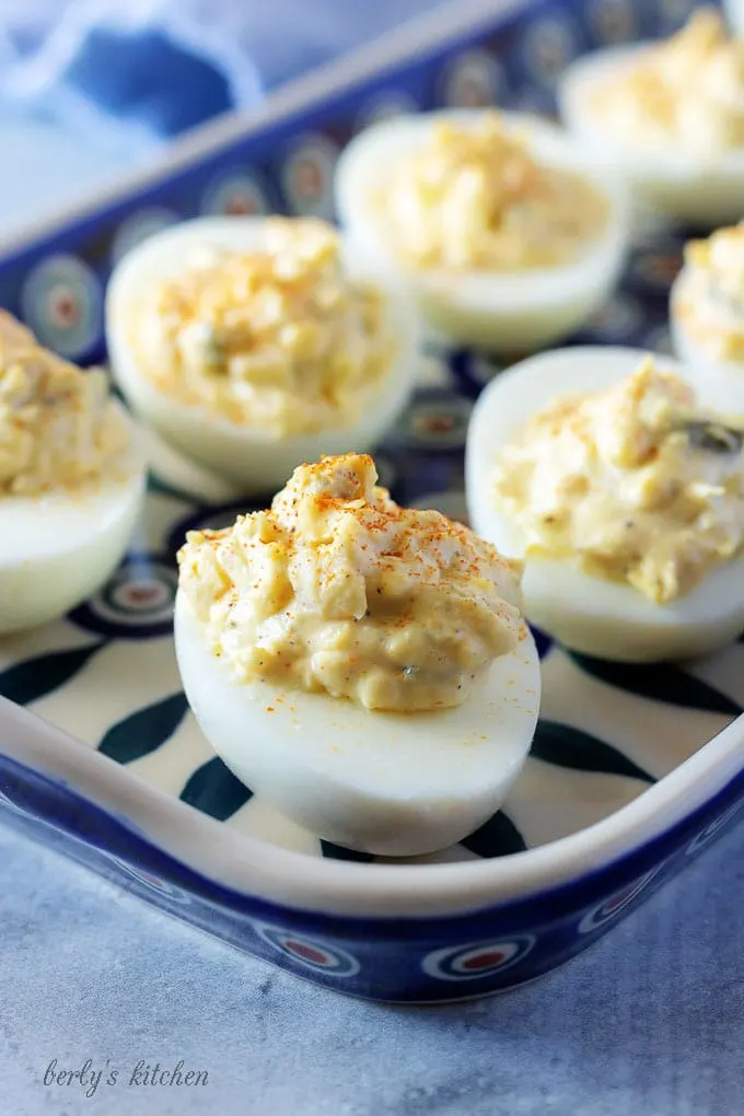 A close-up view of the easy deviled eggs focusing on the eggs sitting on a blue serving platter.