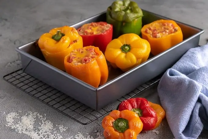 Ground turkey stuffed peppers in a baking dish next to scattered rice and a blue linen.