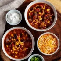 Another top-down photo of the chili with cheddar cheese, diced green onions, and sour cream.