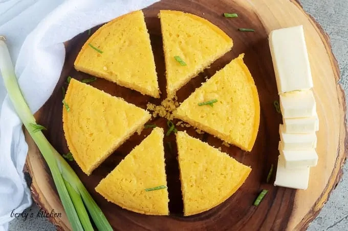 Arial view of buttermilk cornbread on a cutting board with green onion and butter.