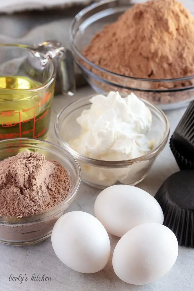 Chocolate cupcakes ingredients like eggs, oil, cake mix, and cream cheese.