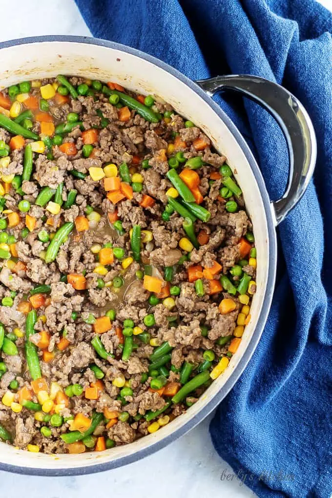 An aerial photo of the cooked meat and veggies in a dtuch oven just before being topped with mashed potatoes.