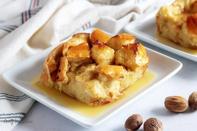 The finished bread pudding, topped with the rum sauce, sitting on a square plate.