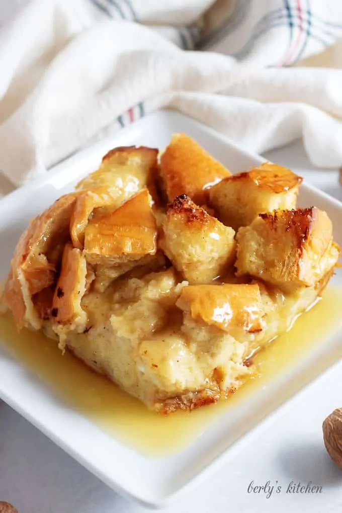 A close-up view of the bread pudding on a square plate accented with fresh nutmeg.