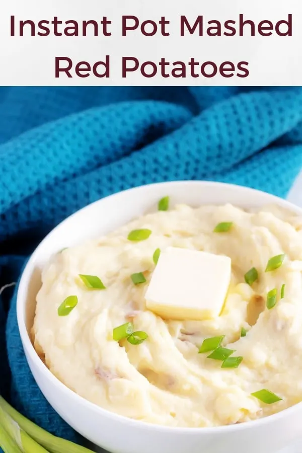 A large picture of the red mashed potatoes in a bowl topped with a pat of butter and sliced green onions.