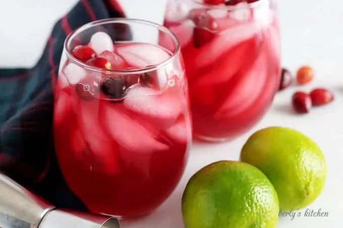 Two stemless wine glasses filled with our vodka cranberry cocktail garnished with fresh cranberries.