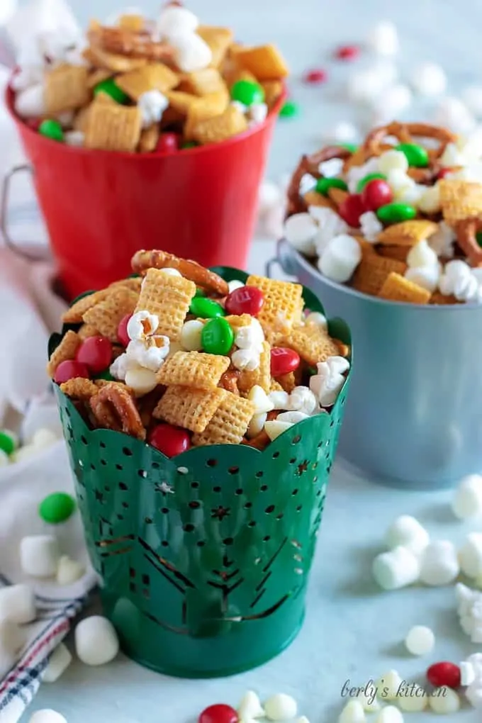 Christmas chex mix in three festive tins.