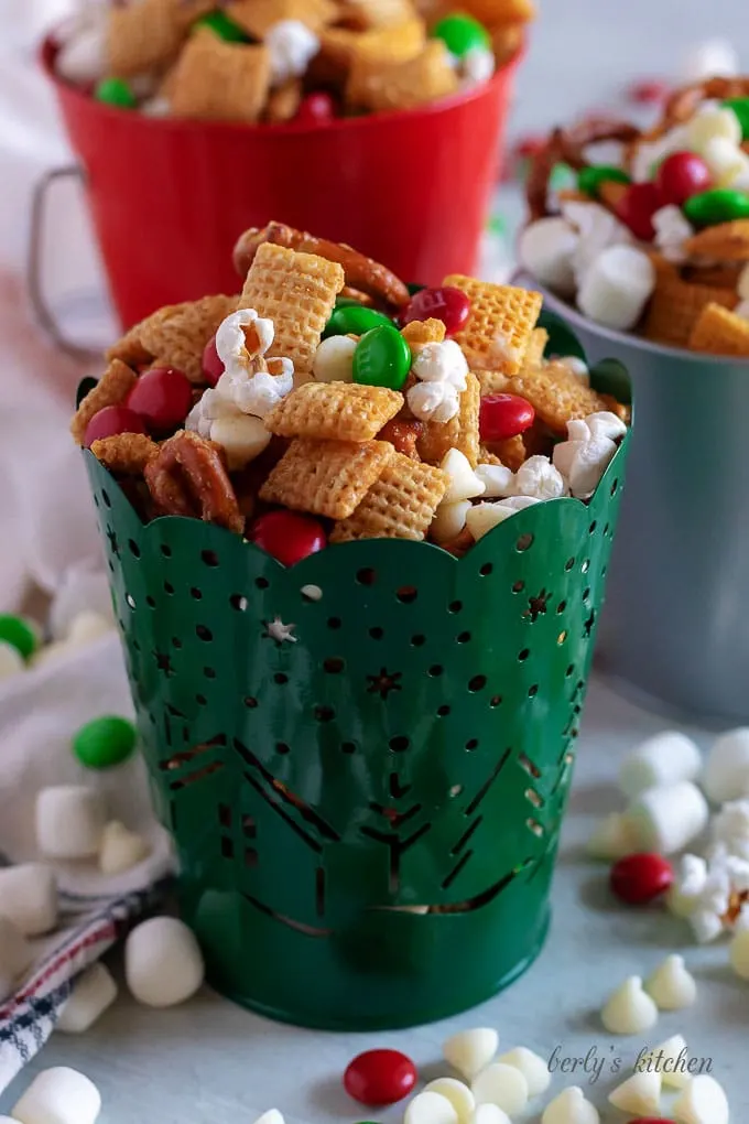 Christmas chex mix in red, green, and silver tins.