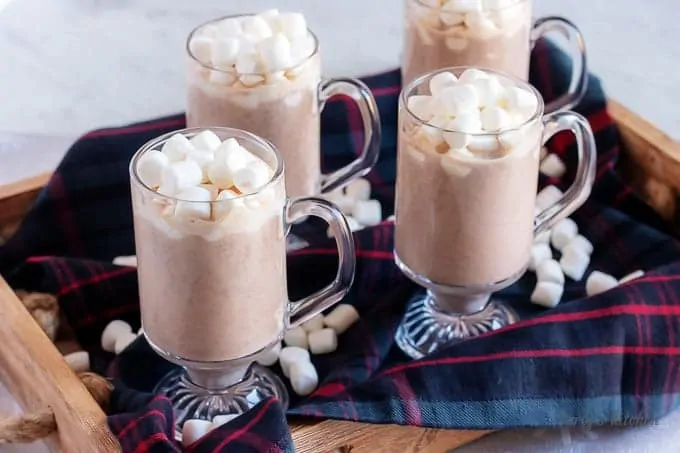 Four mugs of instant pot hot chocolate with marshmallows on a serving tray.