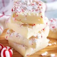 Four pieces of peppermint fudge stacked on a cutting board for presentation.