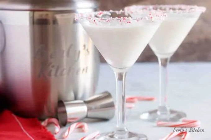 Two peppermint martinis in martini glasses, with a candy cane garnish.