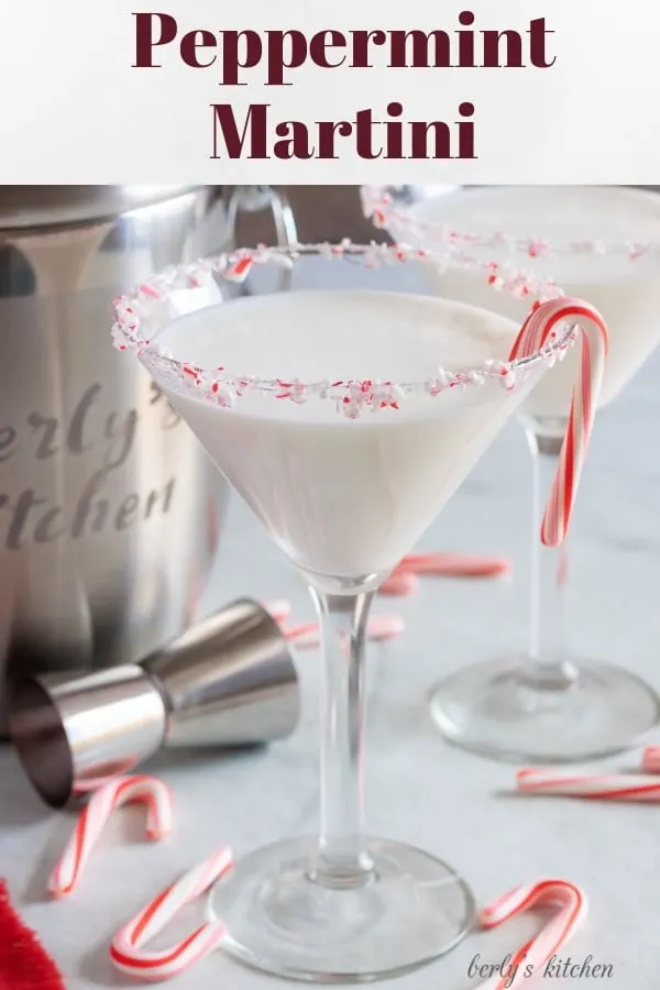 Two finished peppermint martinis with a candy cane garnish, and rimmed with crushed candy canes.