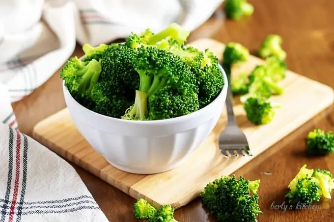 The steamed broccoli in a small white bowl with a fork.