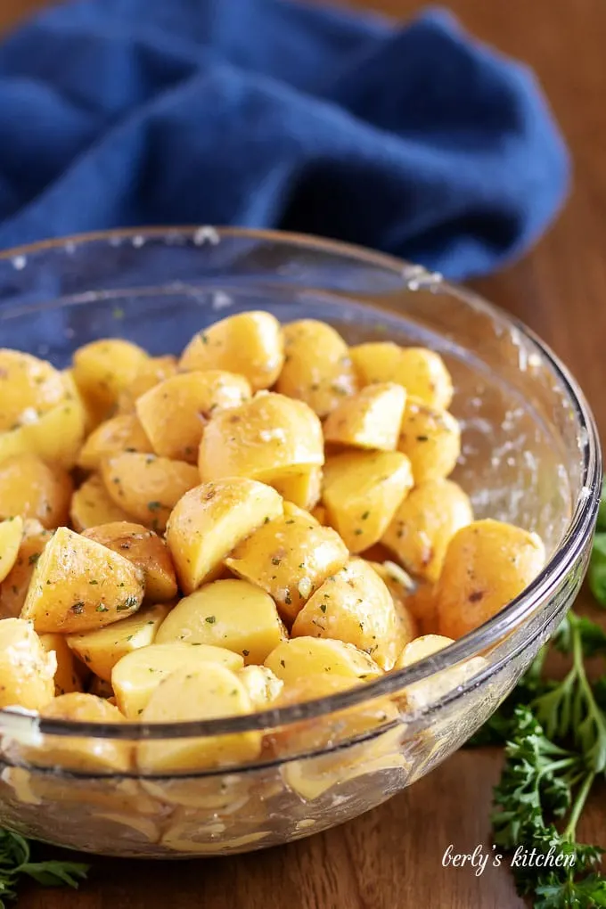 The diced potatoes, in a mixing bowl, tossed with oil, and spices.